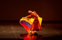 Bailarina con bandera de Colombia en un escenario. 