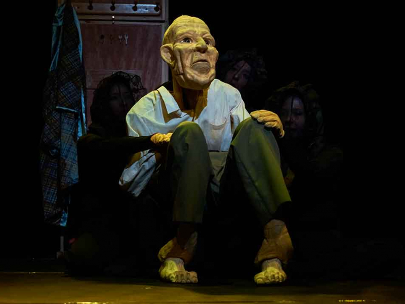 Actor con máscara de hombre viejo sentado en el escenario