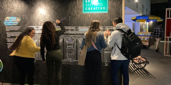 3 mujeres y un joven escribiendo mensajes de un muro negro