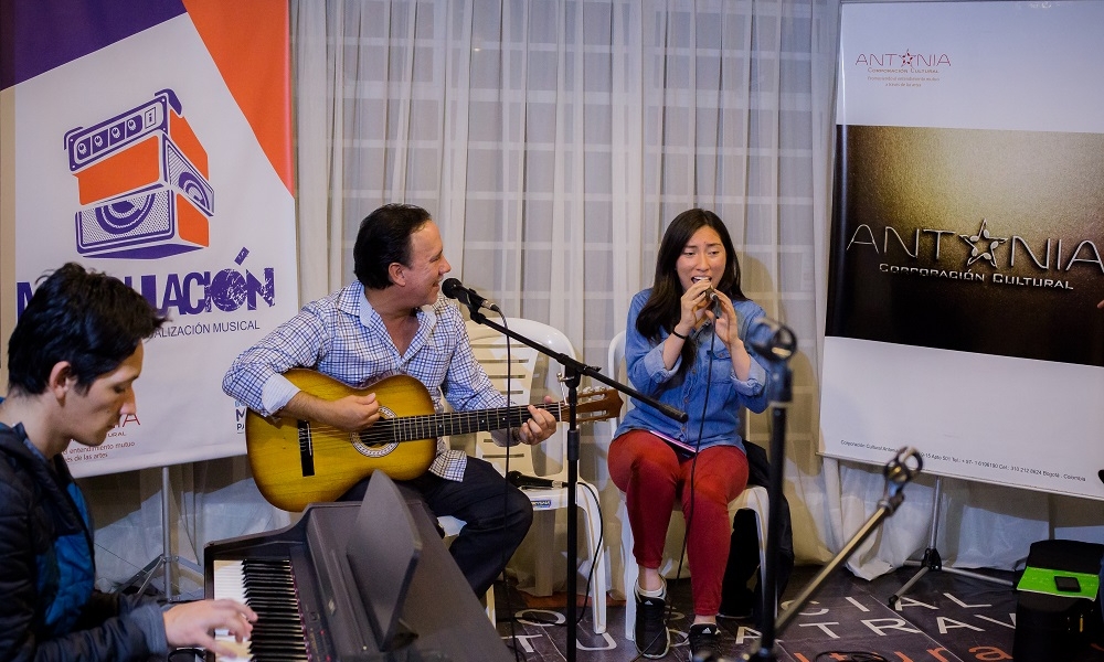 hombre y mujer sentados tocando guitarra y cantando 