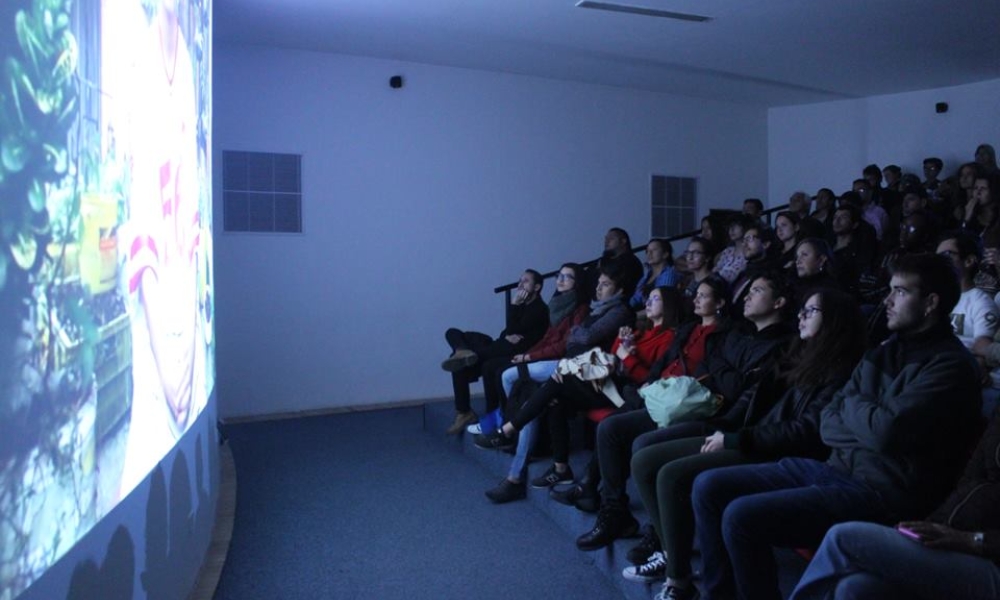 un grupo de personas frente a una pantalla viendo una audiovisual