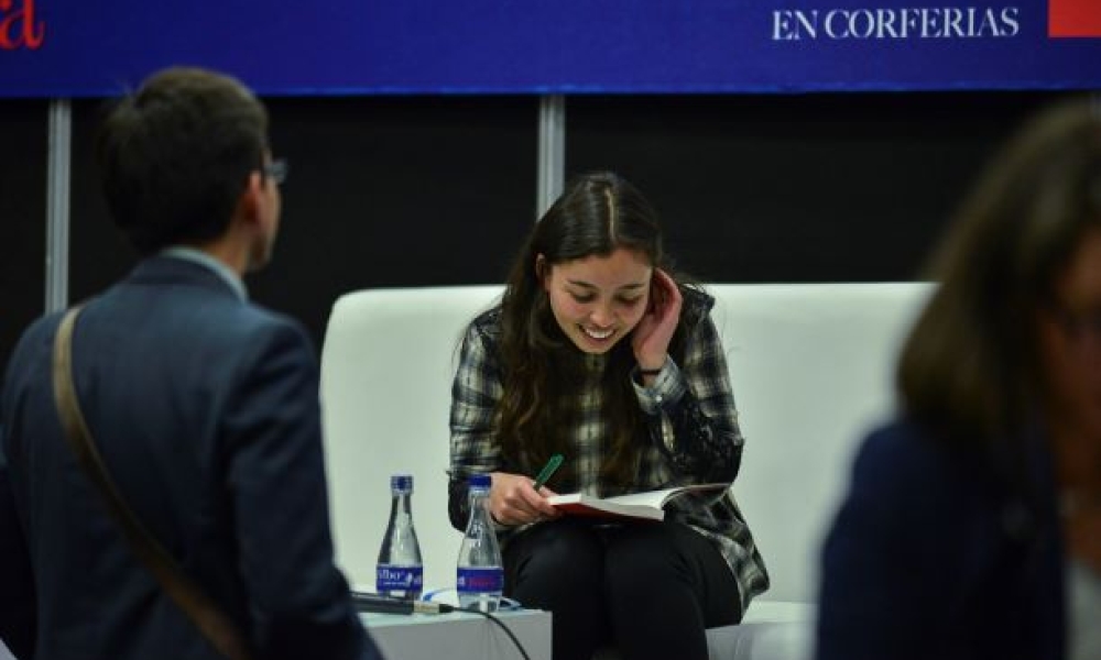 Mujer lee libro en una silla blanca.