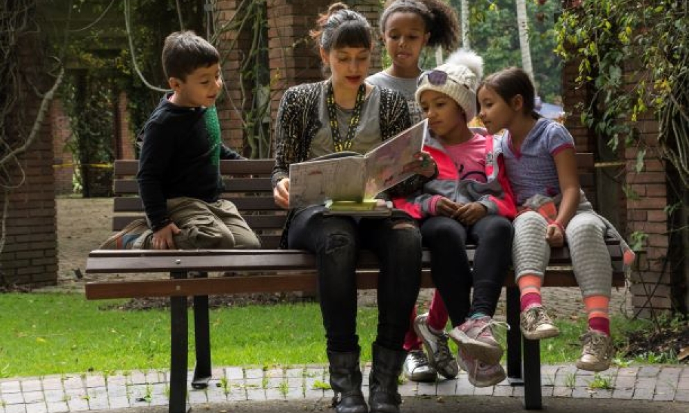 Mujer lee libro a niños