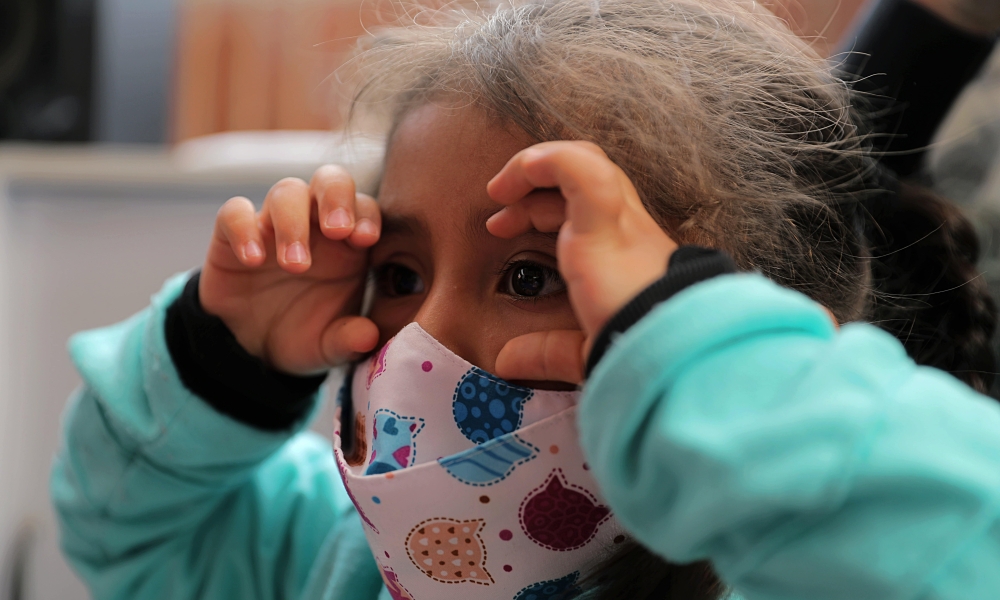 Niña jugando a los binoculares con sus manos.