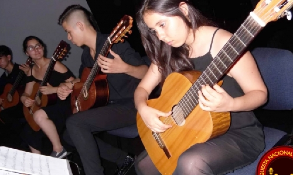 Joven interpretando la guitarra vestida de negro