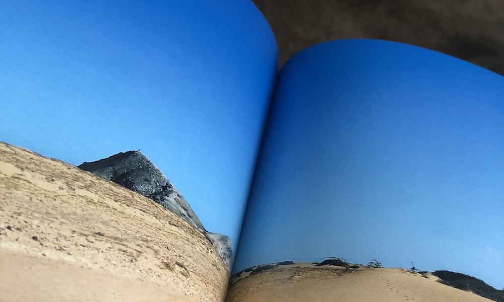 Libro abierto con imagen de playa en su interior. 