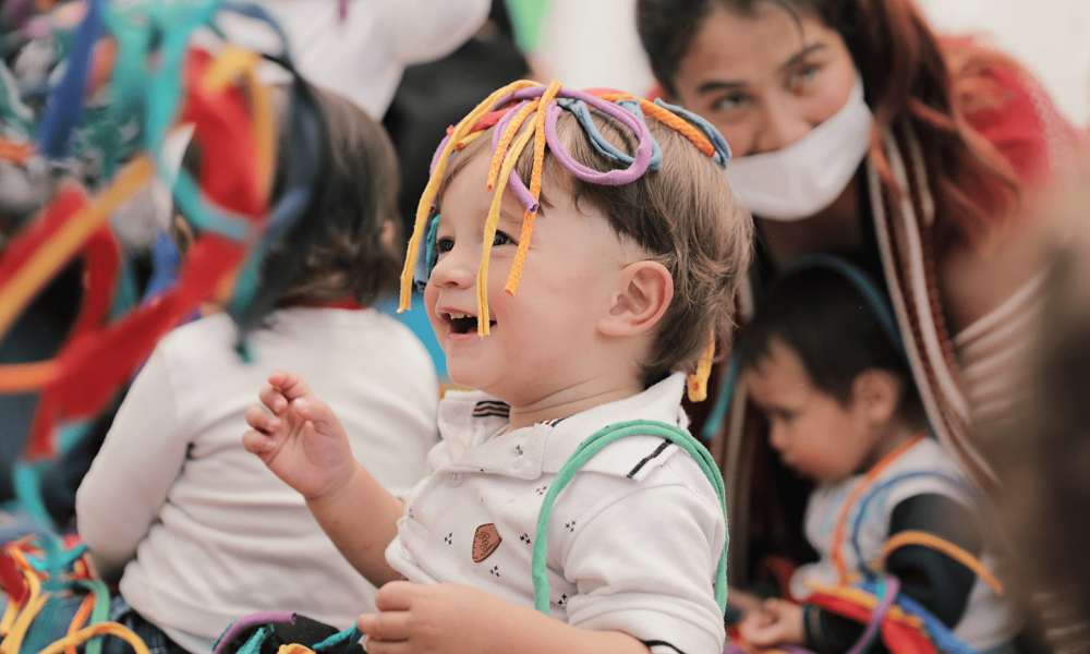 Bebé disfrutando de un laboratorio artístico de día y con más niños al fondo.