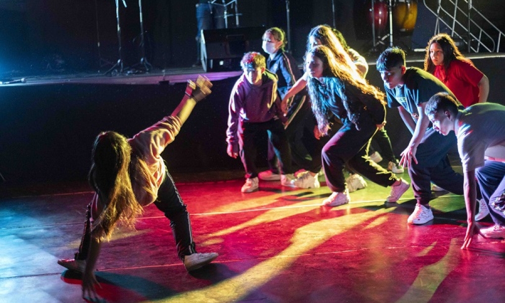 Una mujer baila break dance miestras un grupo de mujeres la observa