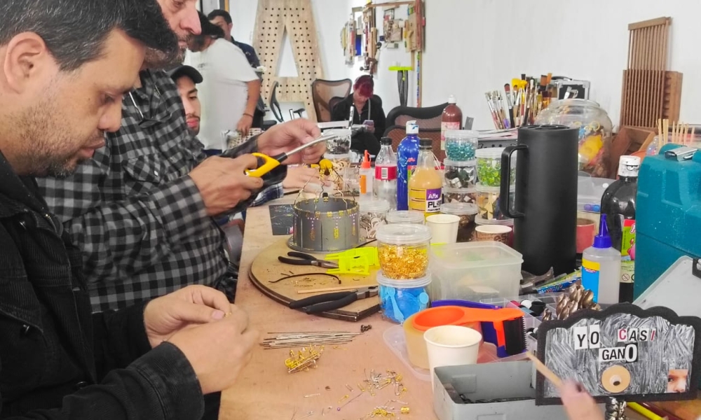 Hombres trabajando con materiales reciclados en una mesa 