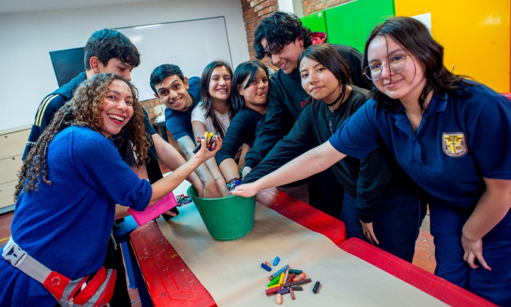 un grupo de jóvenes introducen sus manos en un balde que contiene elementos de pintura