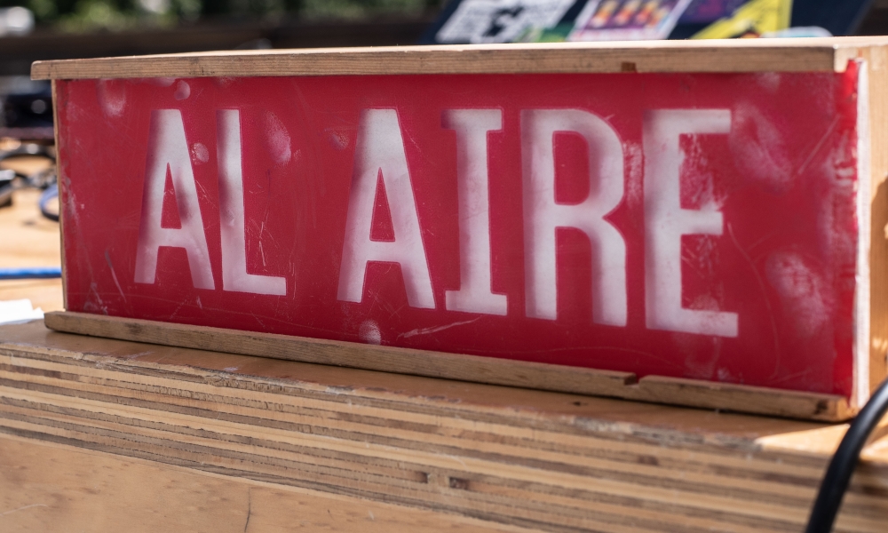 Letrero con aviso "AL AIRE" sobre una mesa en medio de la socialización de resultados de la Beca CKWEB para radio comunitaria.