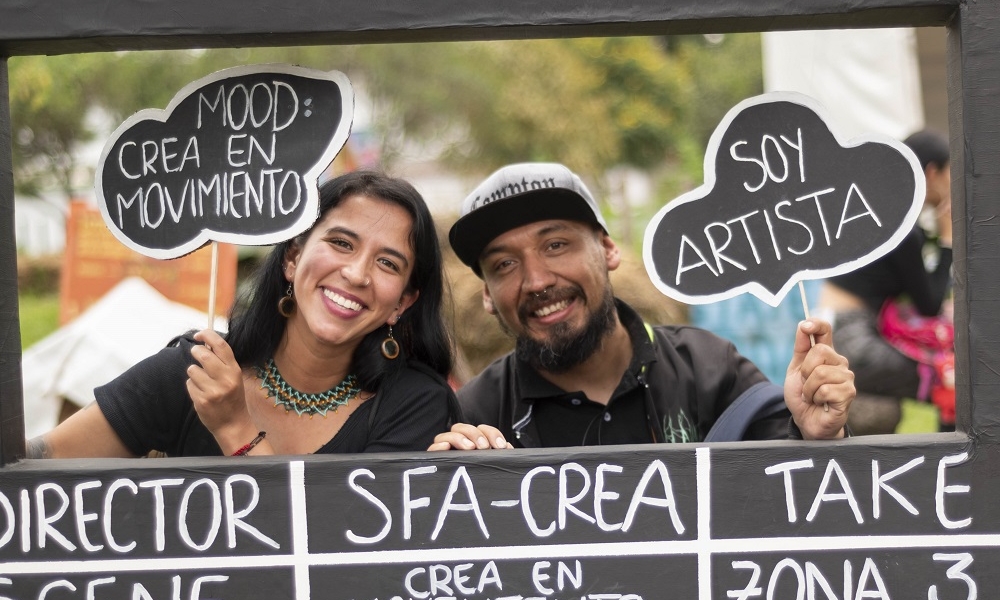 dos personas sonrien mientras sostienen un fotografama de cine gigante. Fotografía por Lina Pachón