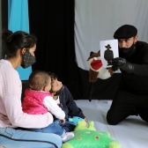 Familia en primera infancia jugando con artista comunitario