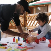 Bebé en primera infancia jugando con su papá a pintar.