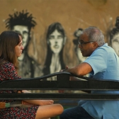 Mujer joven hablando con un señor en una banca de parque 