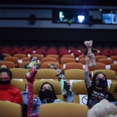 Niños sentados en las sillas de la Cinemateca con títeres en sus manos