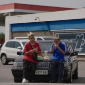 Dos jóvenes sobre un carro comiendo hamburguesa