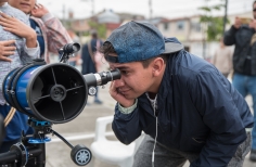 Joven observando por telescopio.