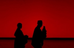 Silueta de hombre y mujer caminando sobre un fondo rojo. 