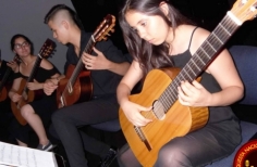 Joven interpretando la guitarra vestida de negro