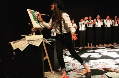 Una joven pinta un lienzo como parte de una escena en una obra de teatro