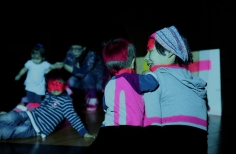 Niños en un cuarto oscuro alumbrados por luces de colores. 