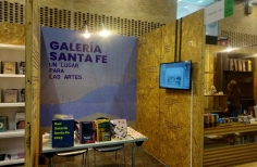 Stand de la Galería Santa Fe en Artbo con libros de arte y una pantalla.
