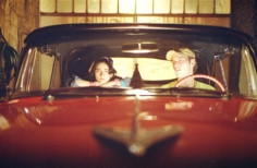 Niño y joven montados en un carro rojo 