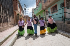 Cinco mujeres caminando por una calle de Ciudad Bolívar de día.