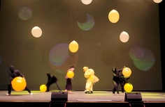 Artistas en tarima jugando con globos y luces de colores