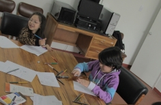 dos niños en una mesa usan colores para plasmar sus ideas en un papel