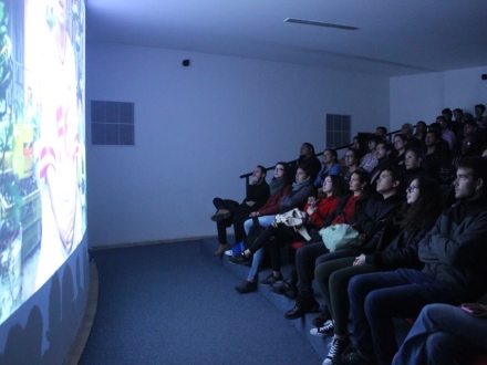 un grupo de personas frente a una pantalla viendo una audiovisual