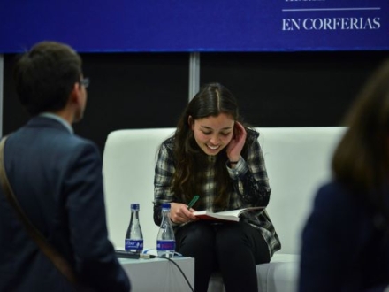 Mujer lee libro en una silla blanca.