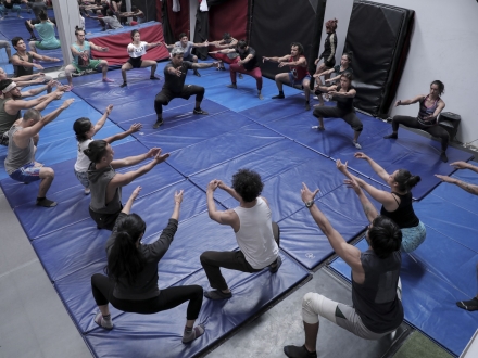 Acróbatas en actividad práctica, agachados haciendo ejercicios del taller.