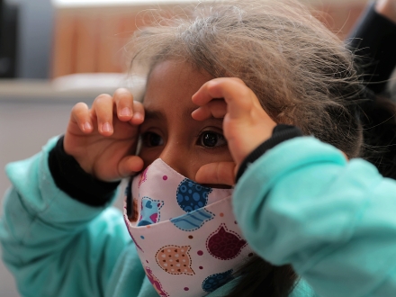 Niña jugando a los binoculares con sus manos.