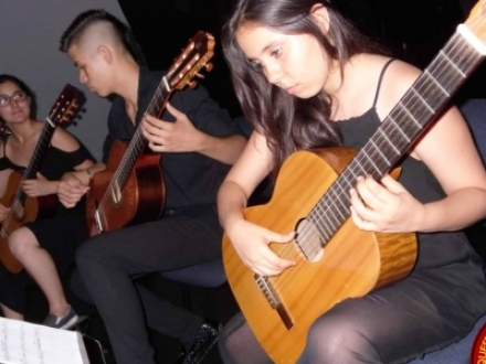 Joven interpretando la guitarra vestida de negro