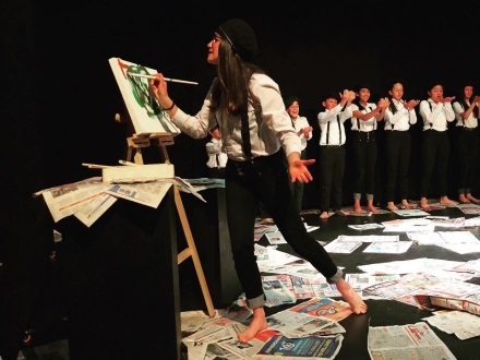 Una joven pinta un lienzo como parte de una escena en una obra de teatro