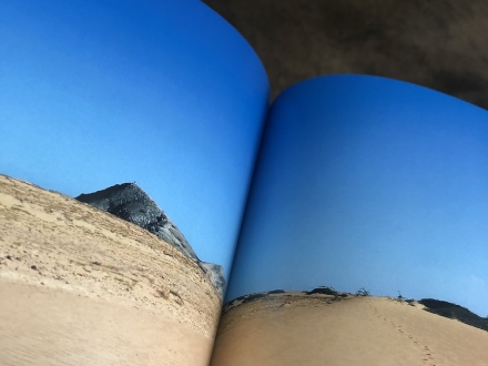 Libro abierto con imagen de playa en su interior. 