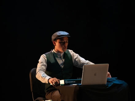 joven sentado frente a una pantalla de computador, una escena teatral