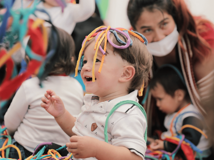 Bebé disfrutando de un laboratorio artístico de día y con más niños al fondo.