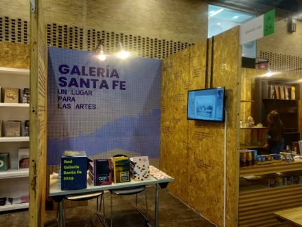 Stand de la Galería Santa Fe en Artbo con libros de arte y una pantalla.