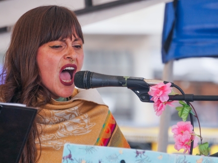 Mujer canta frente a un micrófono de día 