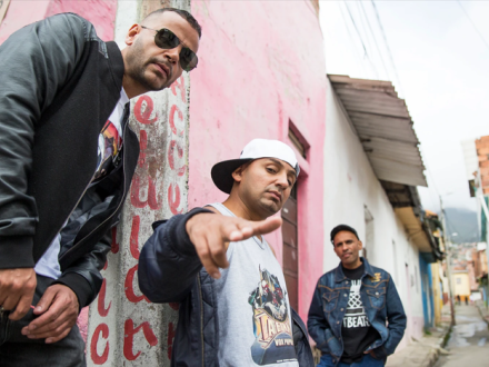 Tres artistas posan en una calle de día