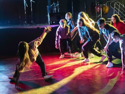 Una mujer baila break dance miestras un grupo de mujeres la observa