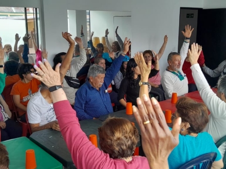 un grupo de adultos mayores están reunidos al rededor de una mesa