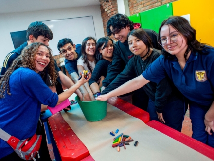 un grupo de jóvenes introducen sus manos en un balde que contiene elementos de pintura