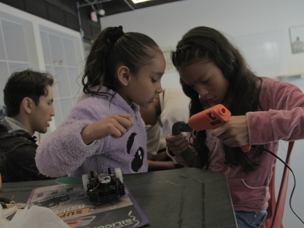 dos niñas pegan con silicona un artefacto