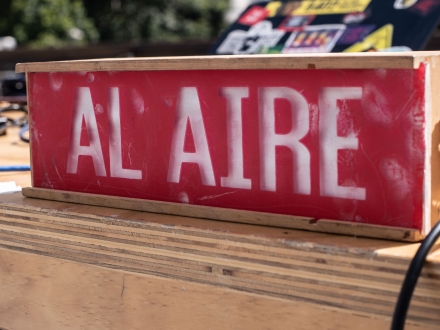 Letrero con aviso "AL AIRE" sobre una mesa en medio de la socialización de resultados de la Beca CKWEB para radio comunitaria.