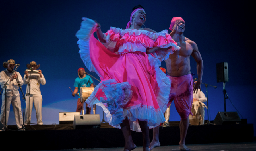 Bailarines danzando en el escenario con trajes coloridos