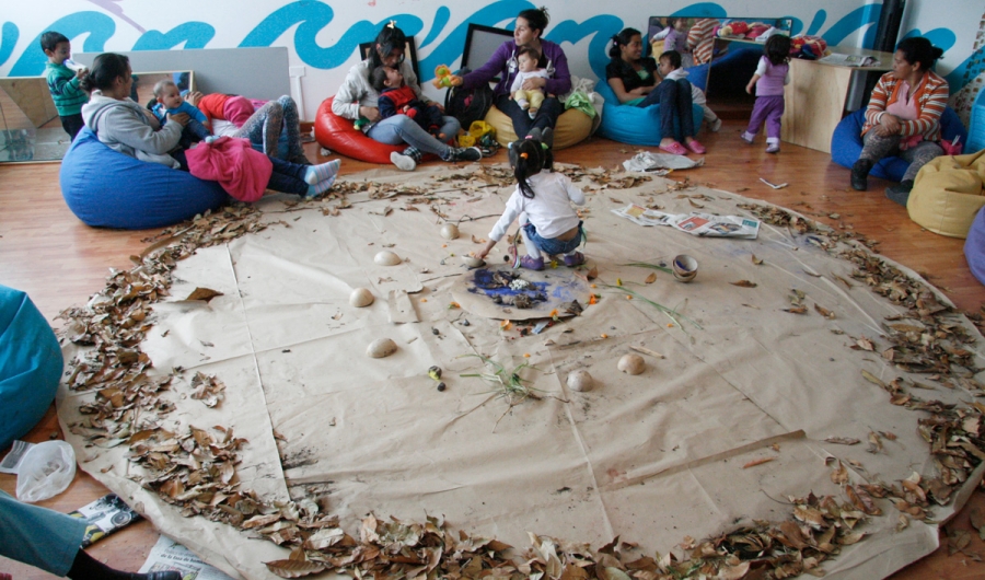 Sala de juegos con niños y madres participando en una actividad